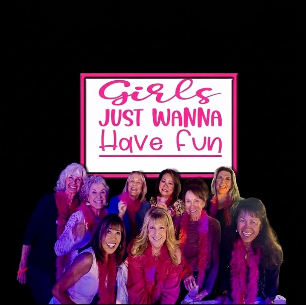 Group of women posing under the Girls Just Wanna Have Fun neon sign